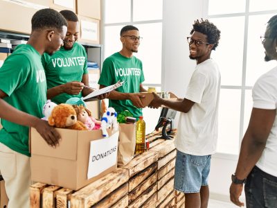 Group of young african american volunteers helping people at charity center.